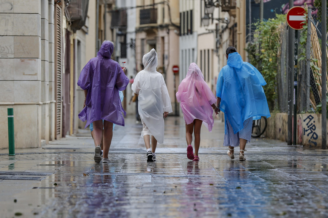 Varias personas caminan bajo la lluvia por una calle del centro deValència. EFE/Manuel Bruque