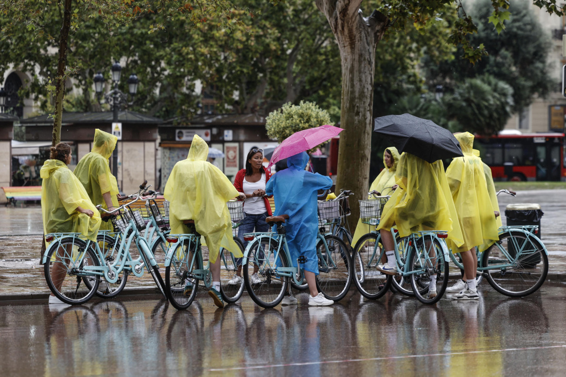 Un grupo de turistas en bicicleta cubiertos con chubasqueros. EFE/Biel Aliño/Archivo