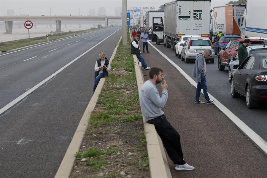 Varios conductores aguardan junto a sus vehículos en la V-30 junto al nuevo cauce del Turia este miércoles. EFE/Biel Aliño