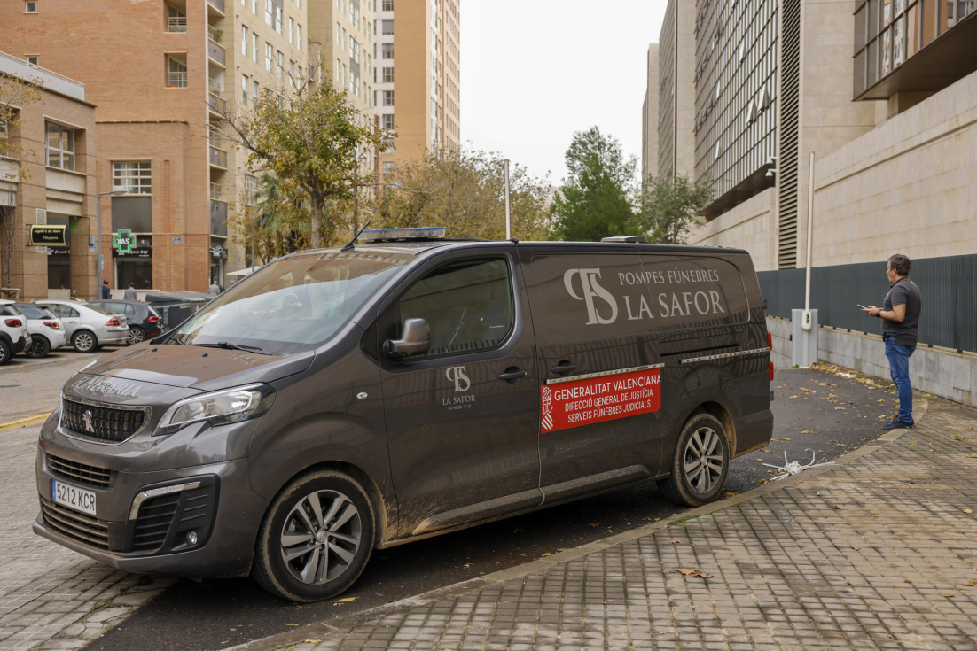 Una persona aguarda junto al vehículo del retén fúnebre estacionado en la Ciudad de la Justicia donde se encuentra el instituto de medicina legal. EFE/Ana Escobar